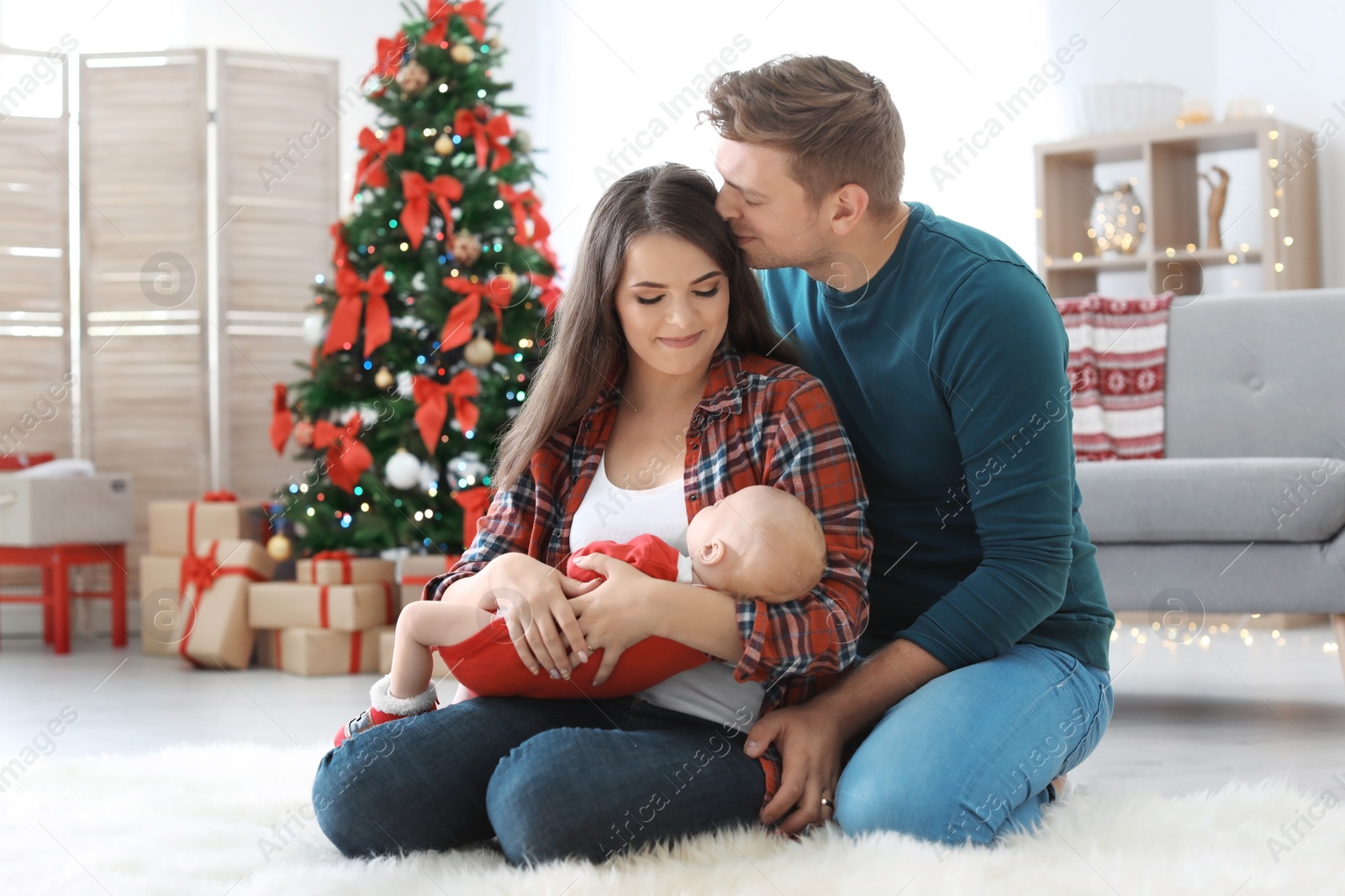 Photo of Happy couple with baby celebrating Christmas together at home