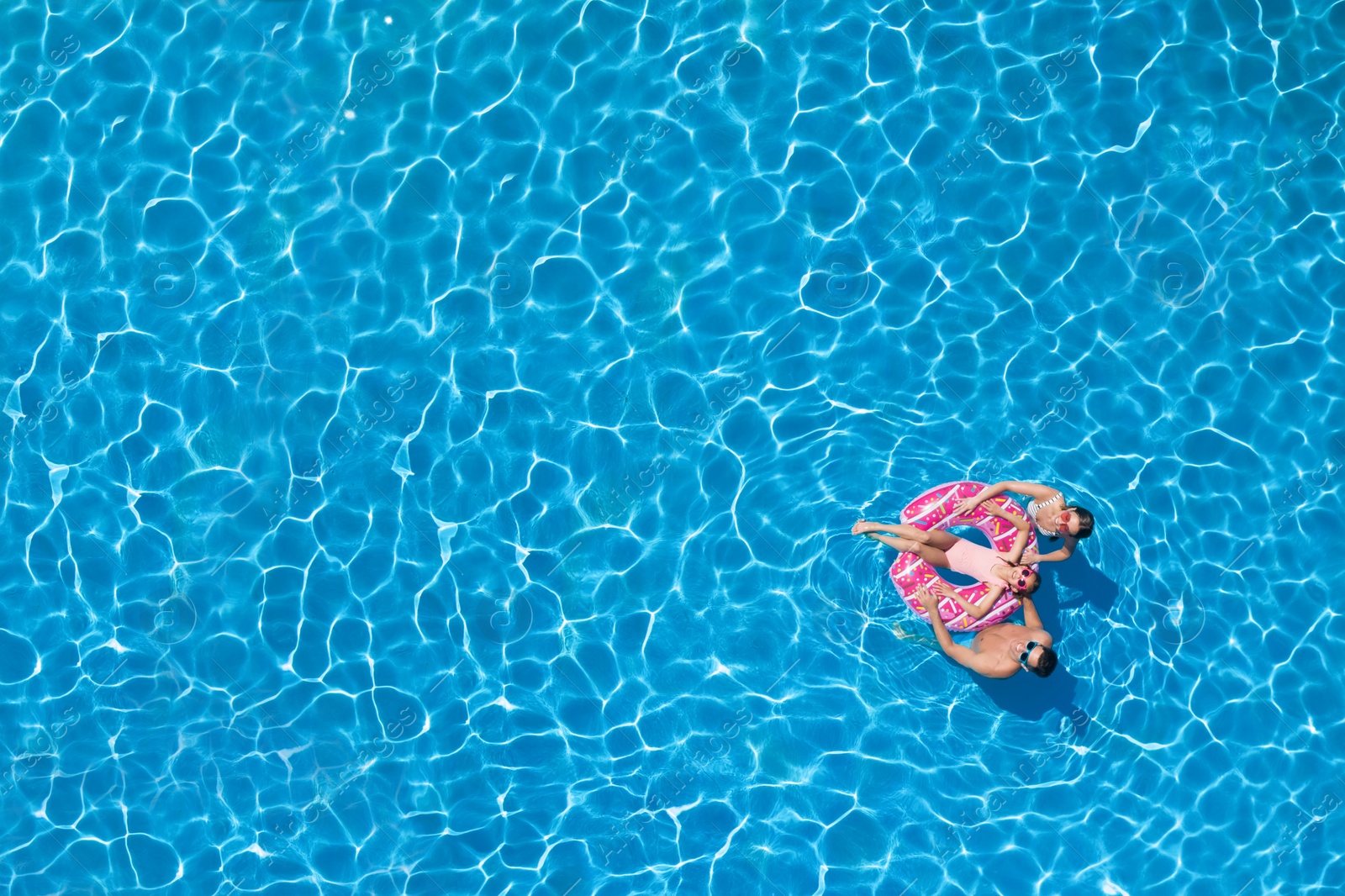 Image of Happy family with inflatable ring in swimming pool, top view. Space for text