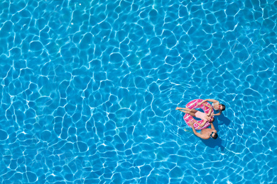 Image of Happy family with inflatable ring in swimming pool, top view. Space for text