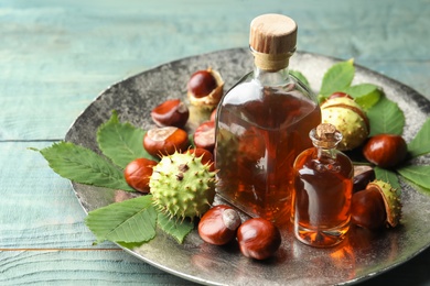 Chestnuts, leaves and bottles of essential oil on blue wooden table