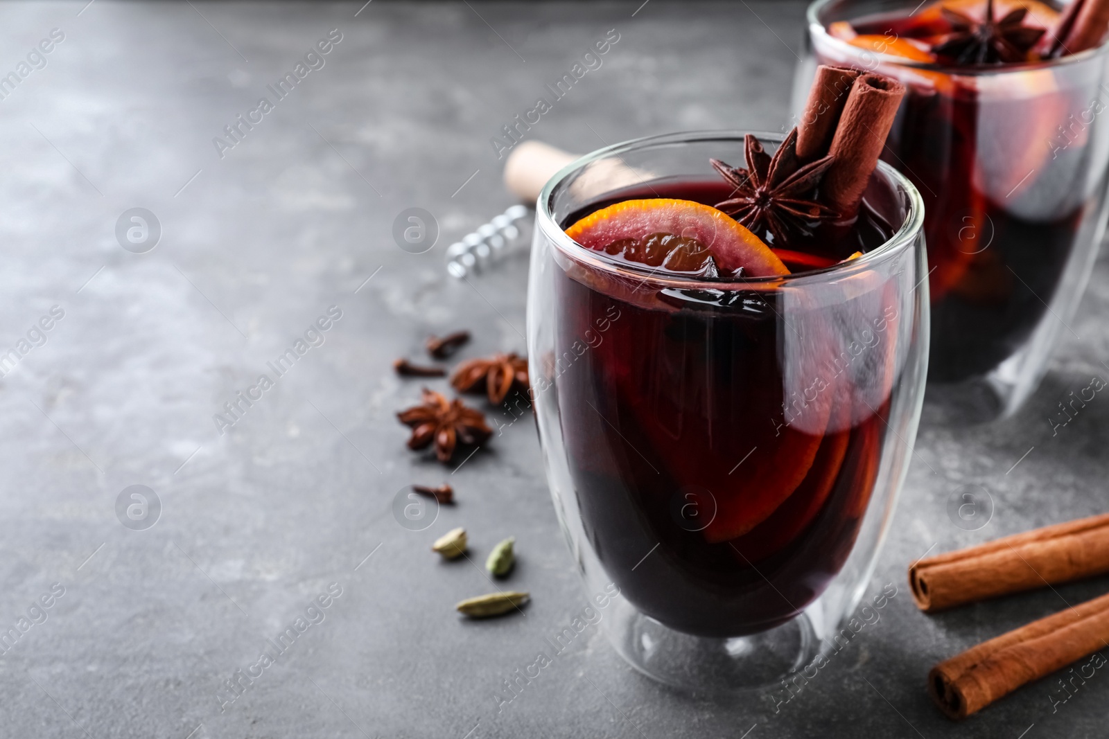 Photo of Aromatic mulled wine on grey table. Space for text