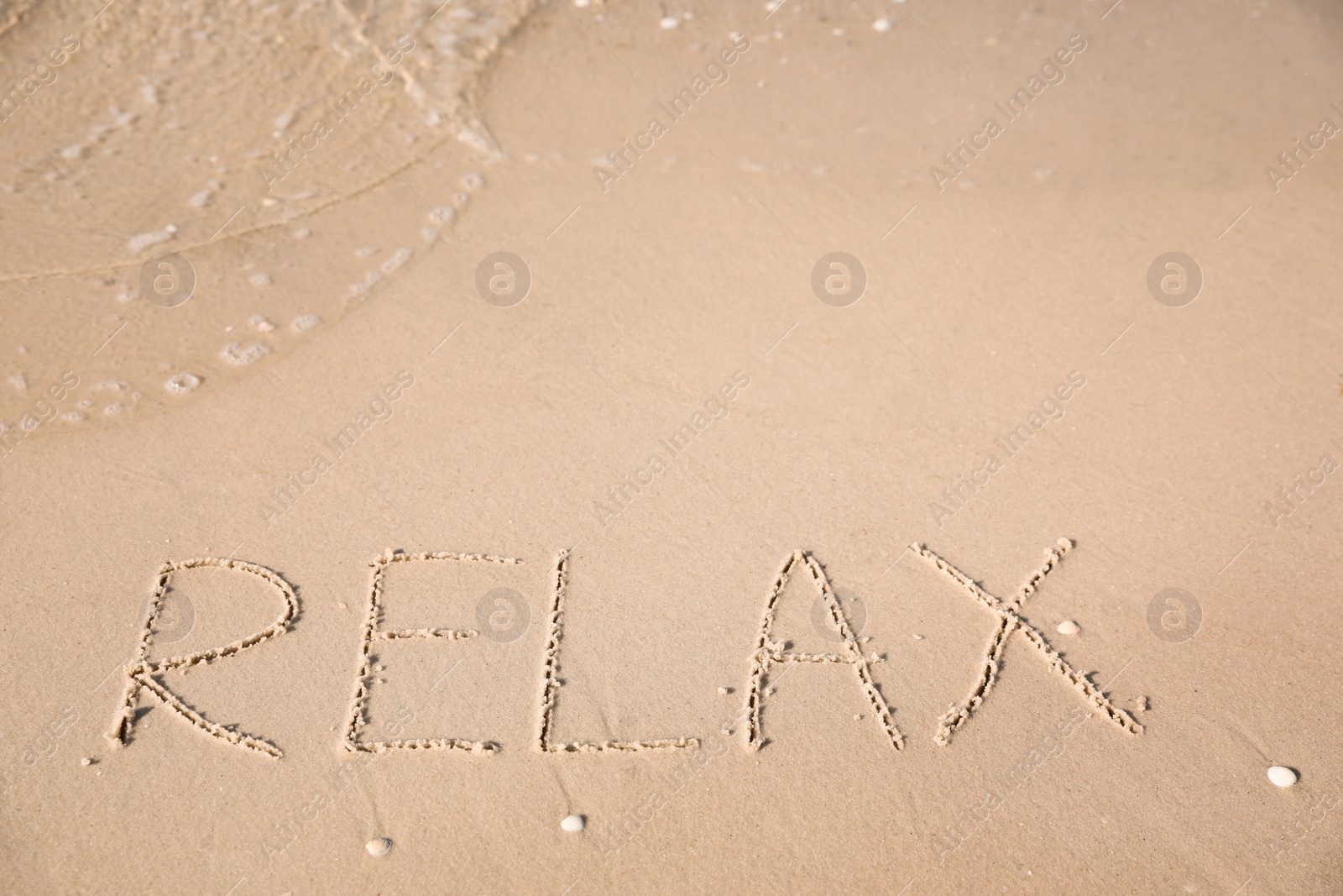 Photo of Word Relax written on sand at beach