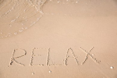Photo of Word Relax written on sand at beach