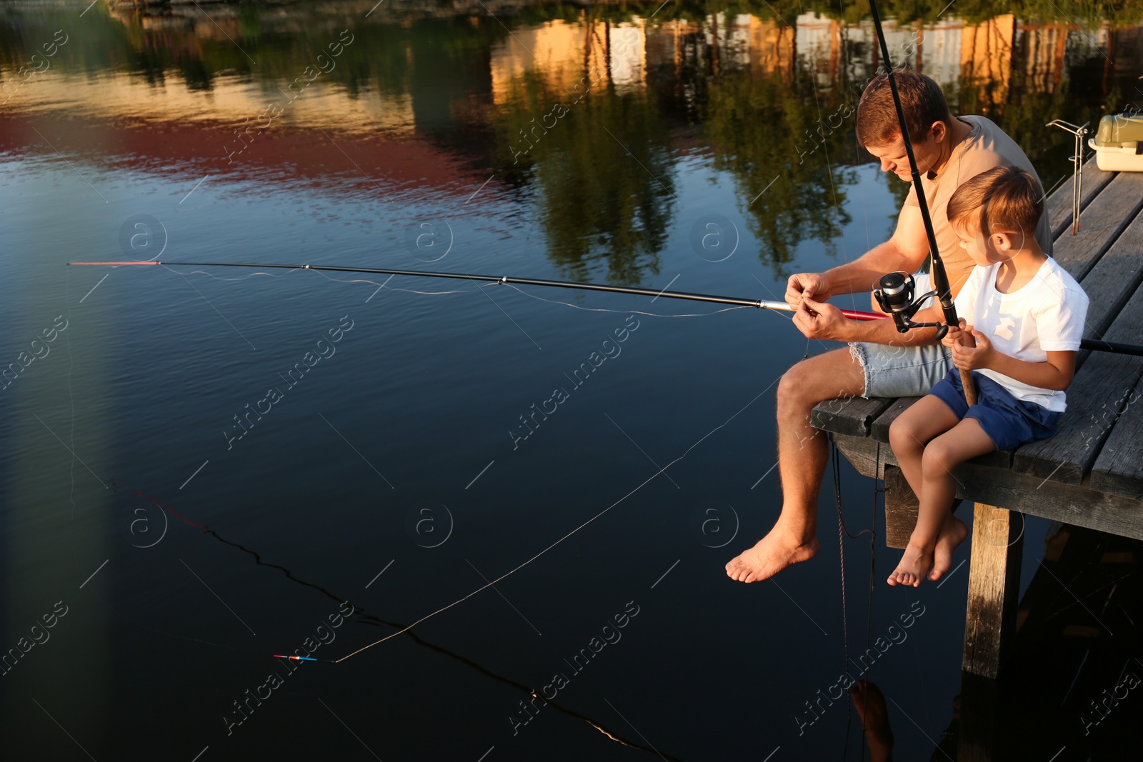 Photo of Dad and son fishing together on sunny day