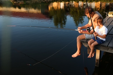 Dad and son fishing together on sunny day