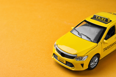 Photo of Yellow taxi car model on orange background. Space for text