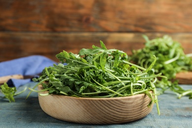 Photo of Fresh arugula leaves on blue wooden table