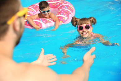 Photo of Father and children having fun in swimming pool, closeup. Family vacation