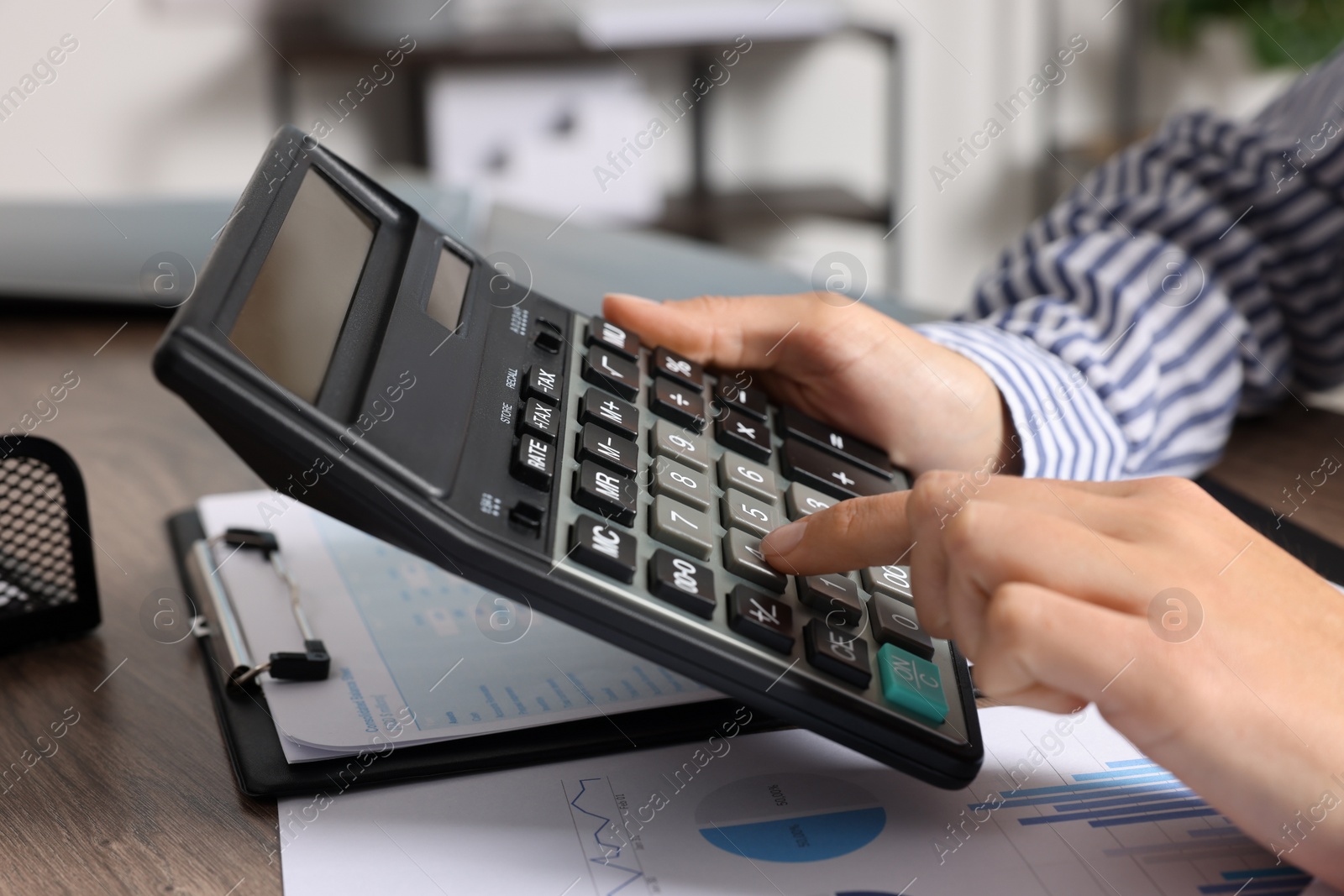 Photo of Woman using calculator at table indoors, closeup