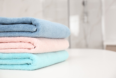 Stack of color towels on white table in bathroom, closeup. Space for text