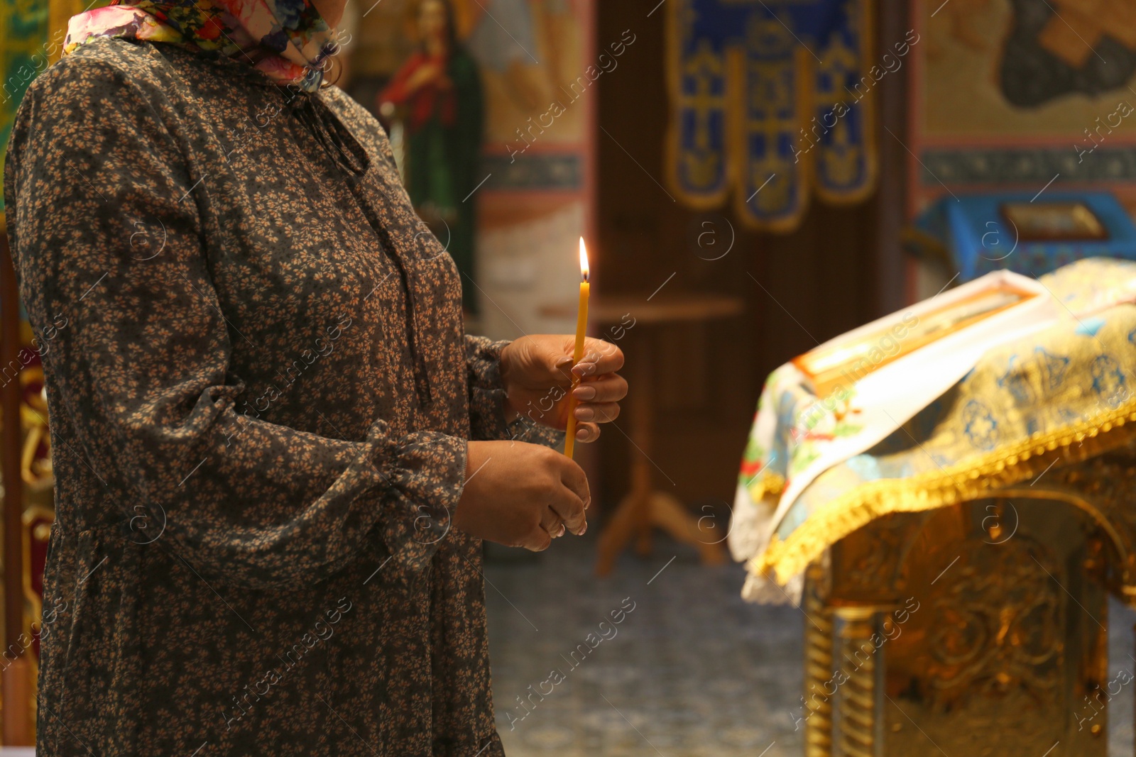 Photo of Mature woman holding candle in church, closeup