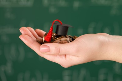 Photo of Woman holding coins and graduation cap against blurred background, closeup. Scholarship concept