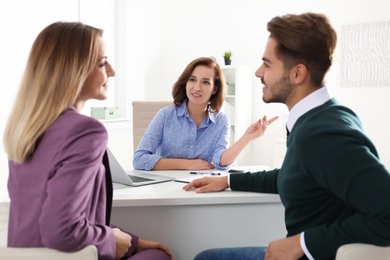 Photo of Real estate agent consulting young couple in office