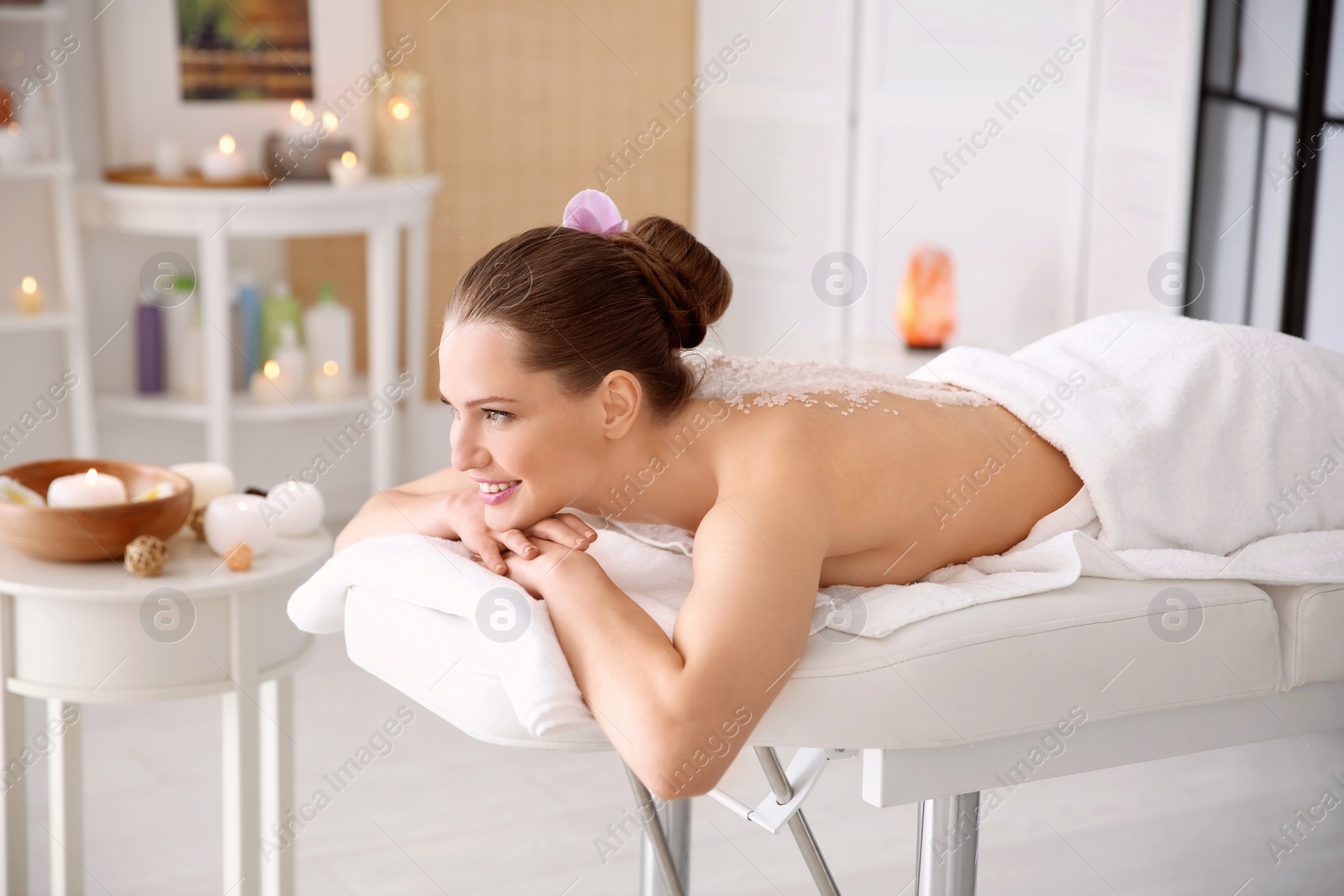 Photo of Beautiful young woman having massage with body scrub in spa salon