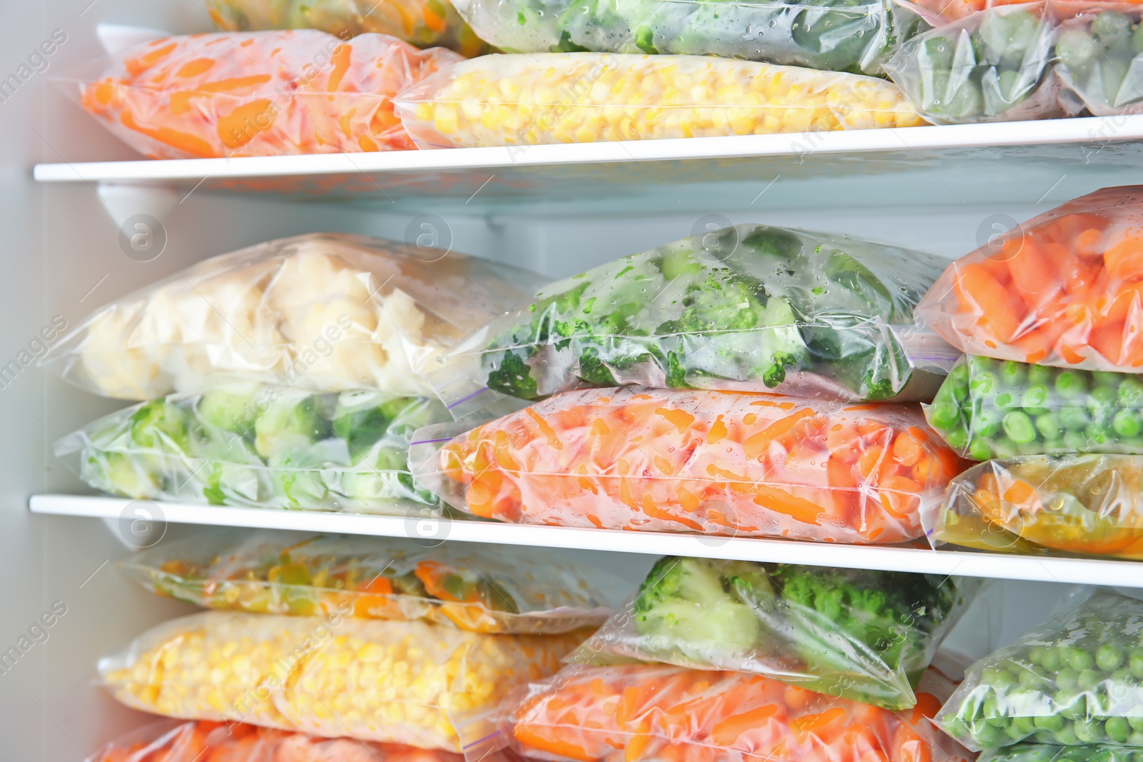 Photo of Plastic bags with deep frozen vegetables in refrigerator