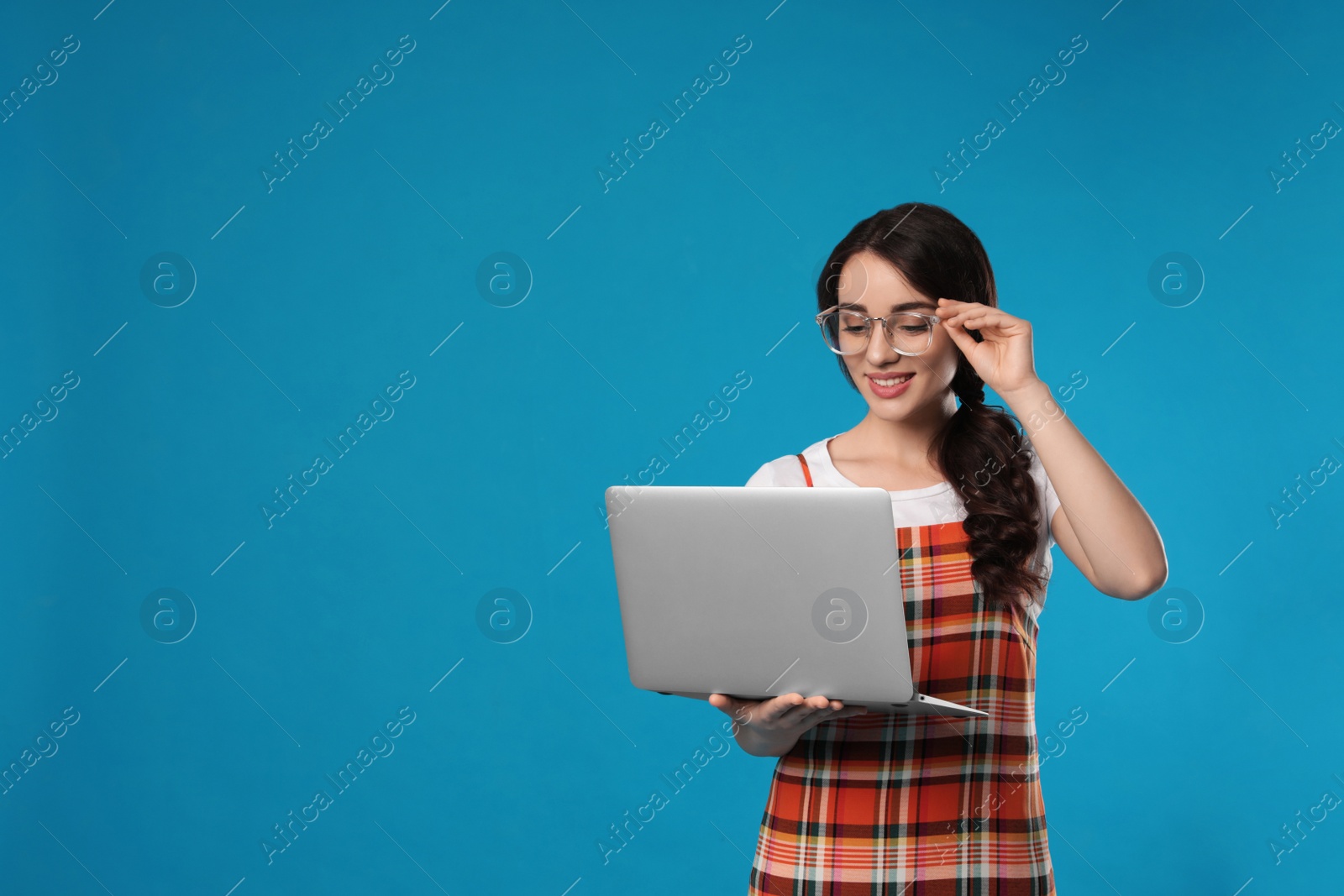 Photo of Young woman with laptop on blue background. Space for text