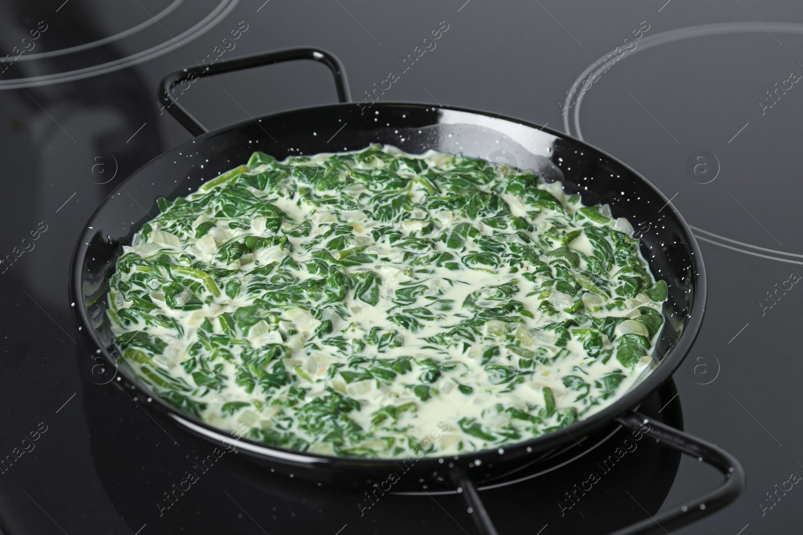 Photo of Tasty spinach dip in frying pan on kitchen stove