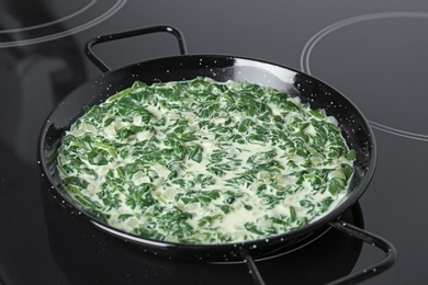 Tasty spinach dip in frying pan on kitchen stove