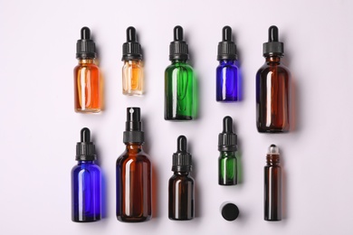 Bottles of essential oils on light background, top view. Cosmetic products