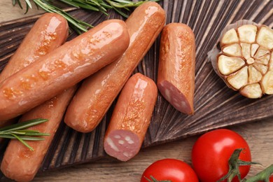 Photo of Delicious vegan sausages, garlic and tomatoes on wooden table, flat lay