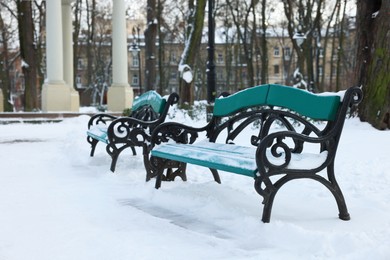 Photo of Green benches and trees in snowy park