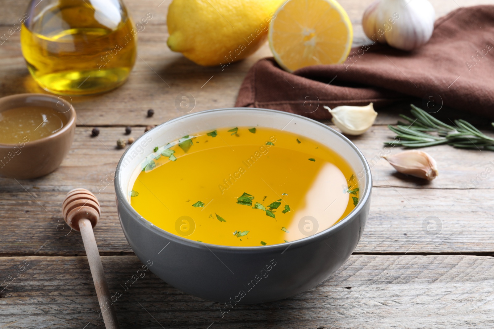 Photo of Bowl with lemon sauce and ingredients on wooden table. Delicious salad dressing