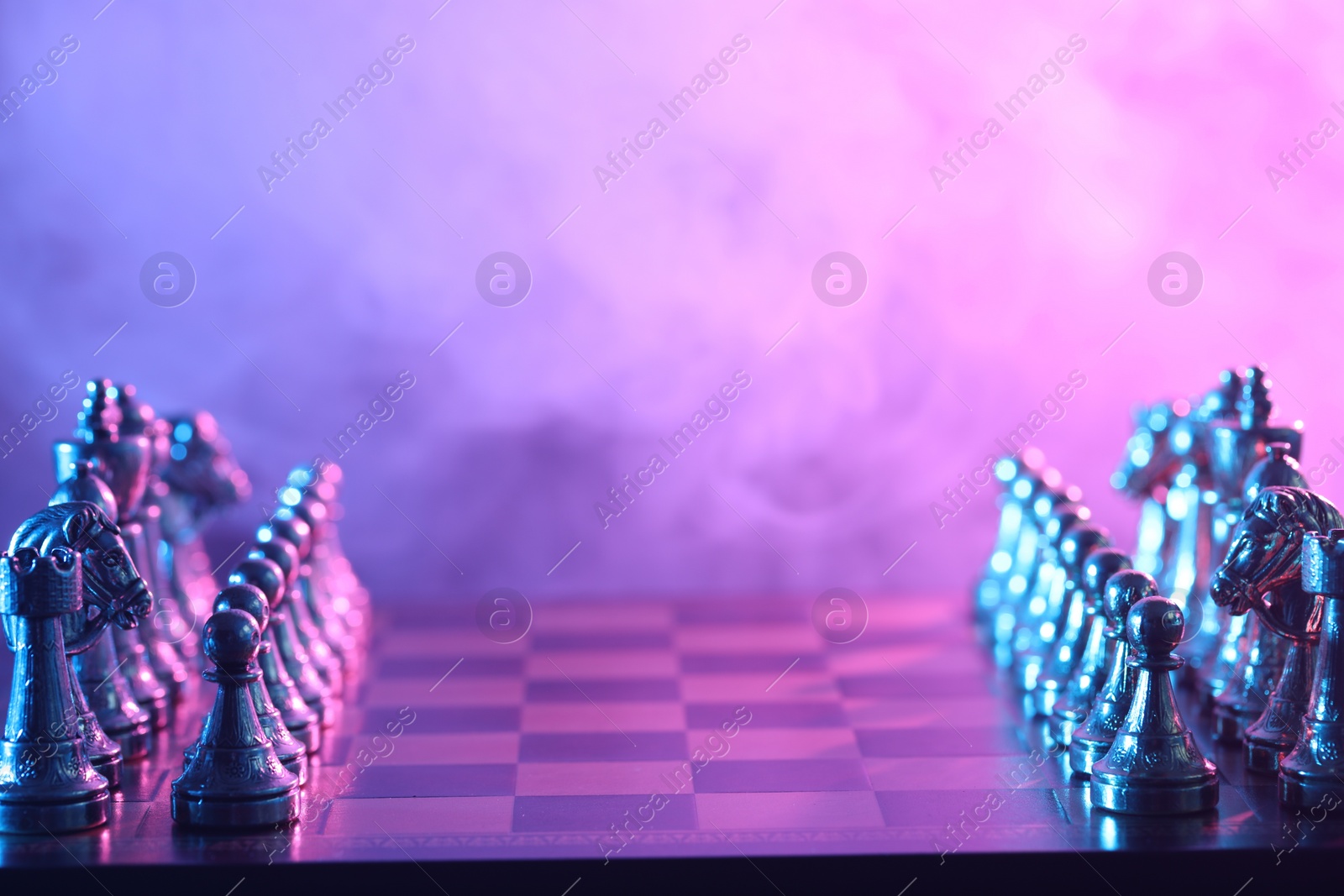 Photo of Set of chess pieces on checkerboard in color light before game, selective focus. Space for text