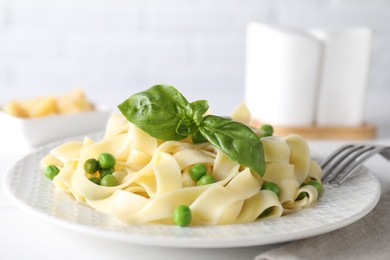 Photo of Delicious pasta with green peas served on white table, closeup