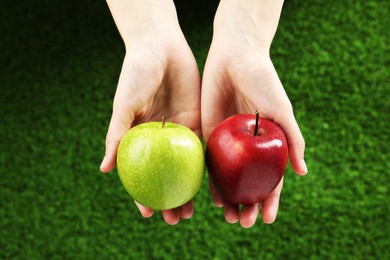 Photo of Woman holding fresh ripe red and green apples outdoors, closeup