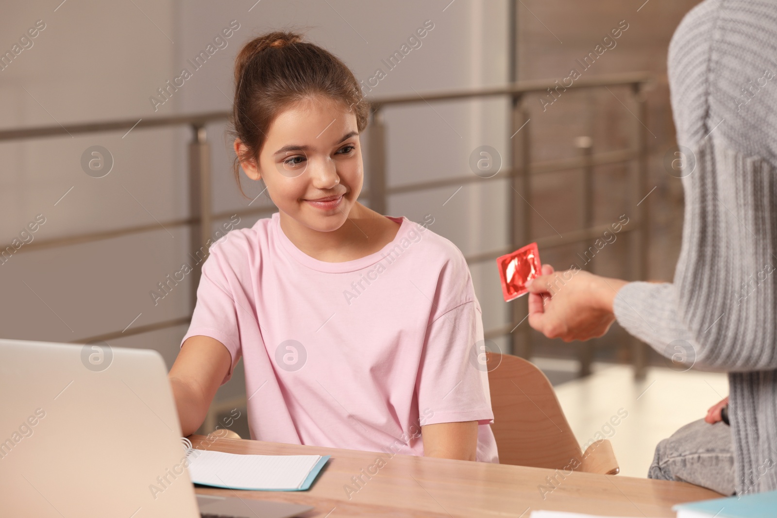 Photo of Mother talking with her teenage daughter about contraception while she doing homework at home. Sex education concept