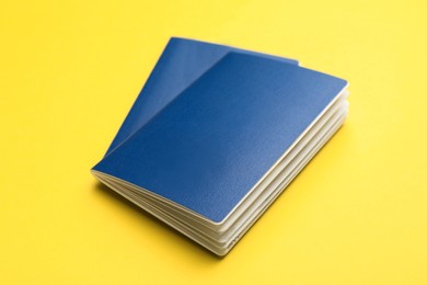 Photo of Two blank blue passports on yellow background, closeup