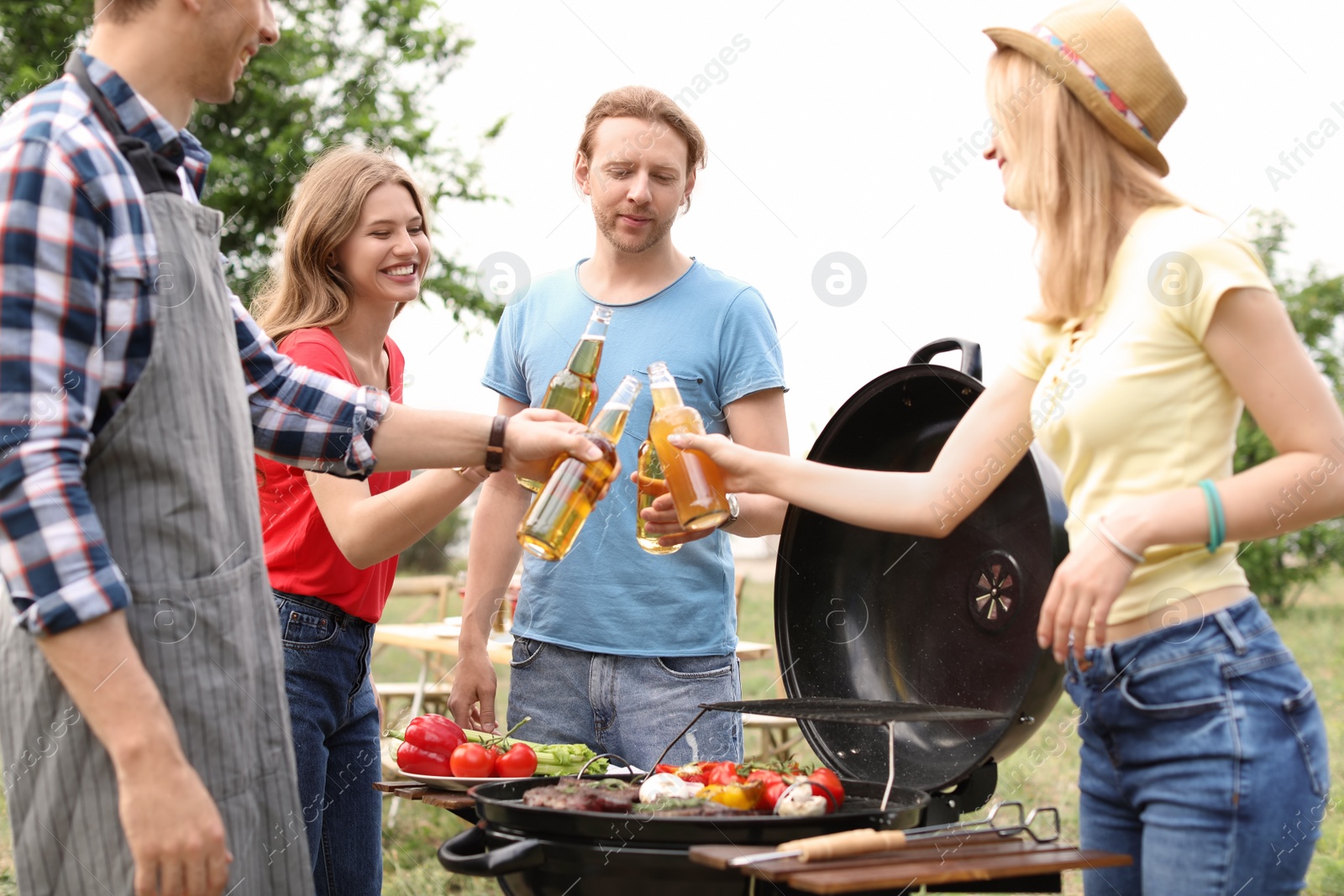 Photo of Young people having barbecue with modern grill outdoors