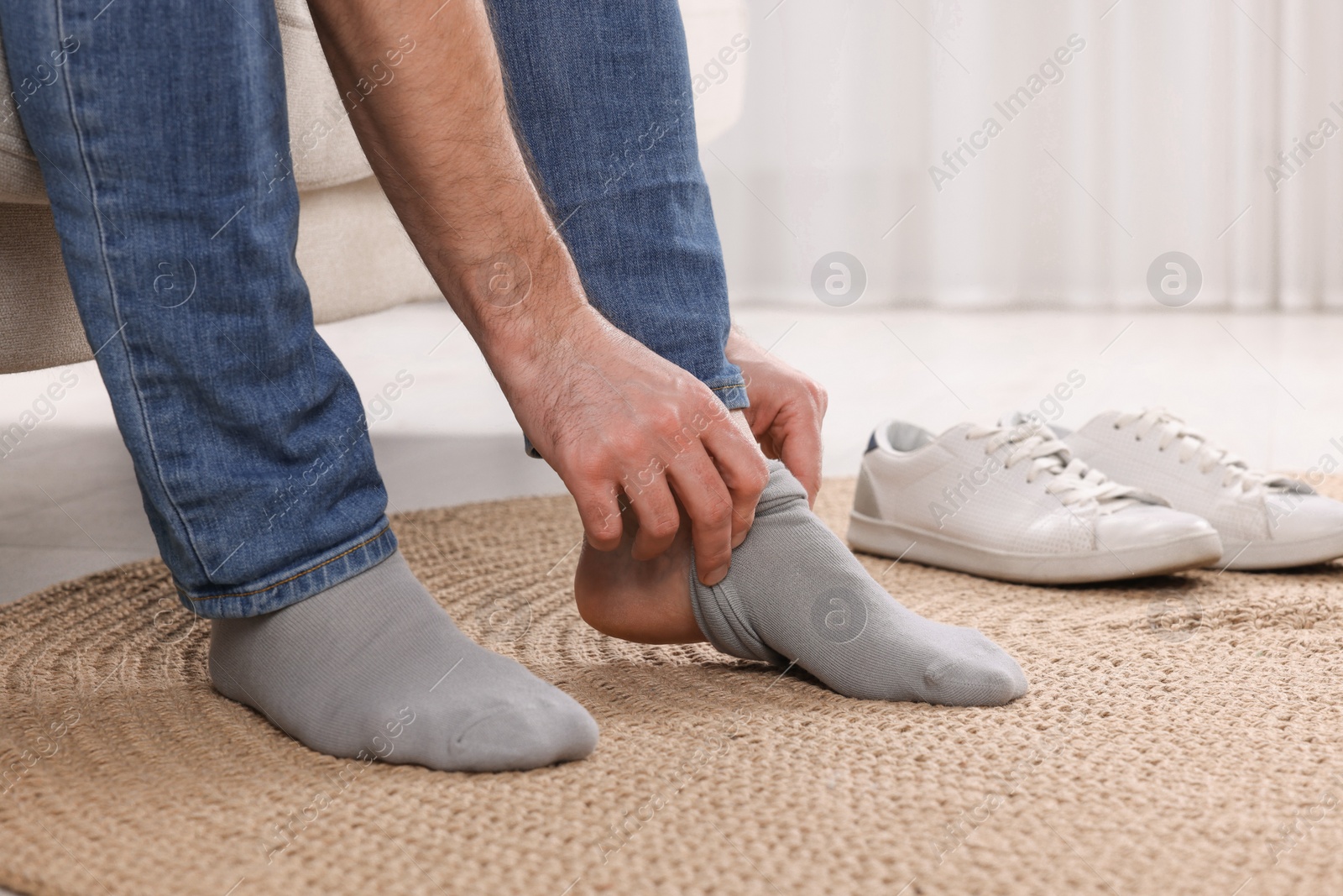 Photo of Man putting on grey socks at home, closeup