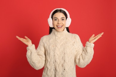 Photo of Beautiful young woman wearing earmuffs on red background