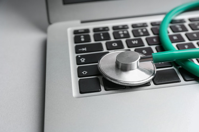 Laptop and stethoscope on light background, closeup. Concept of technical support