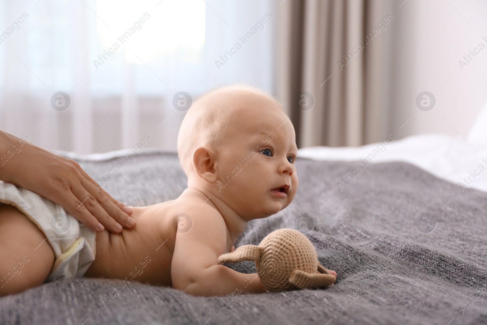 Photo of Young woman massaging cute little baby on bed at home