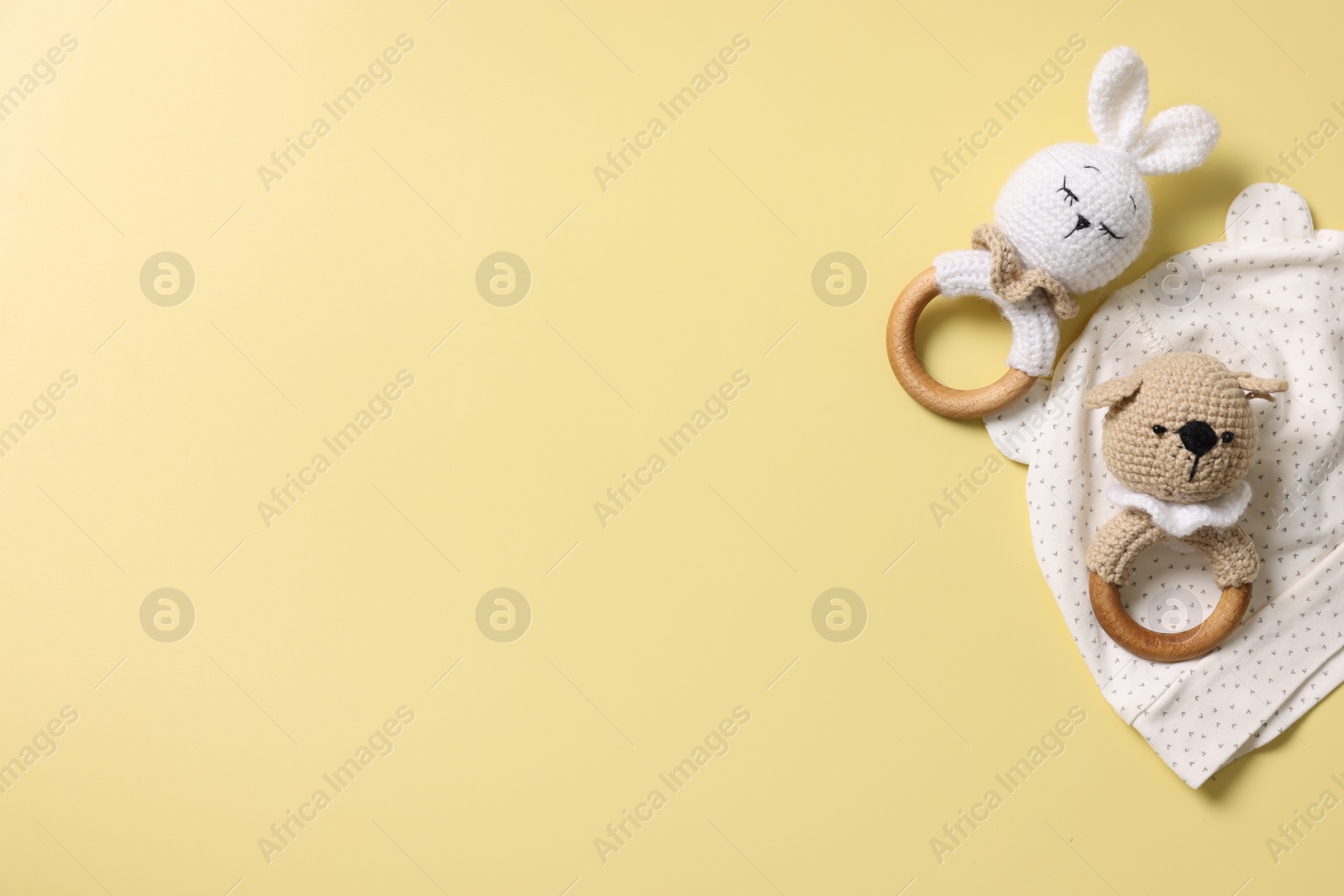 Photo of Baby accessory. Rattles and hat on yellow background, top view. Space for text