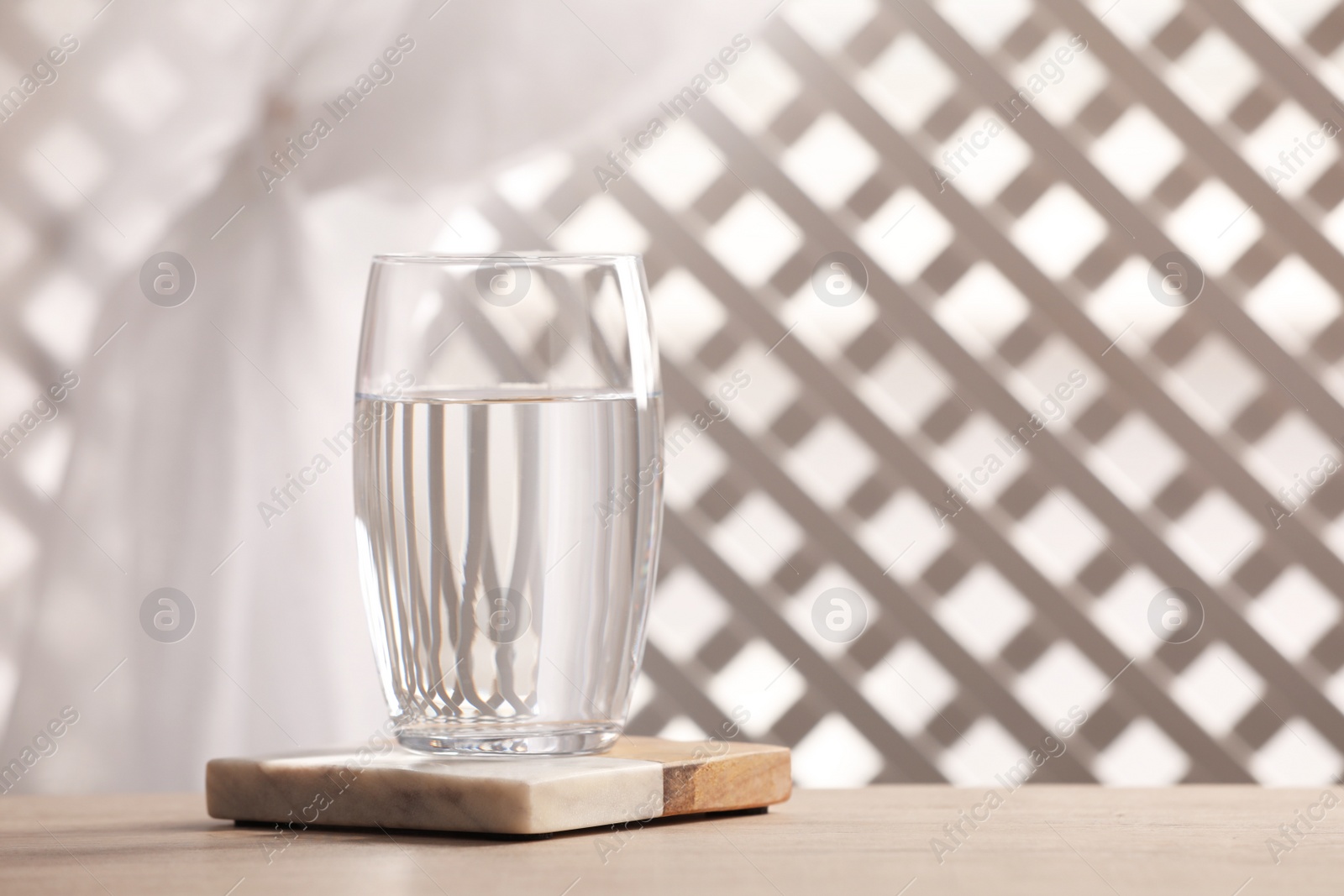 Photo of Glass of pure water on wooden table against blurred background, space for text