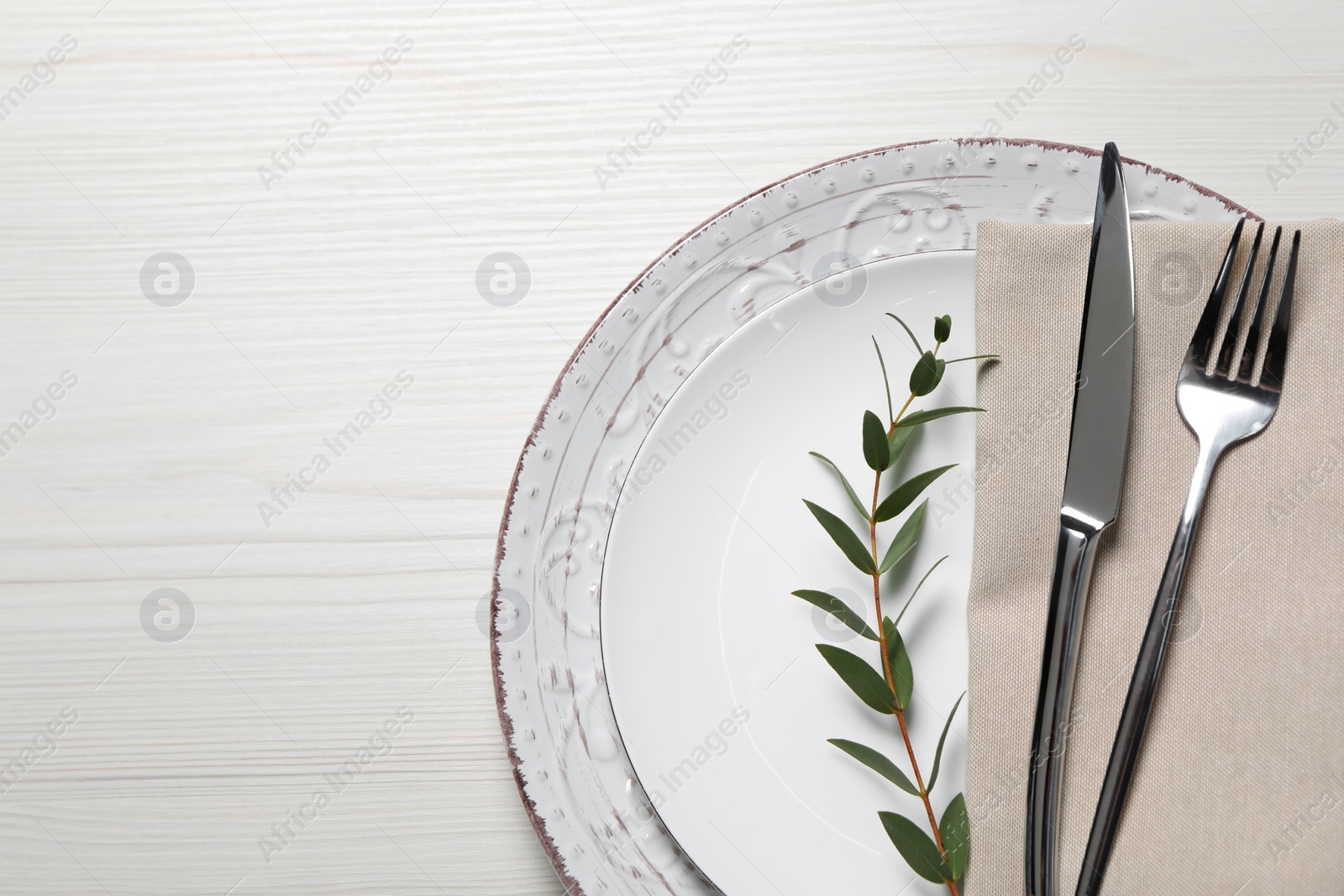 Photo of Stylish setting with cutlery and eucalyptus leaves on white wooden table, flat lay. Space for text