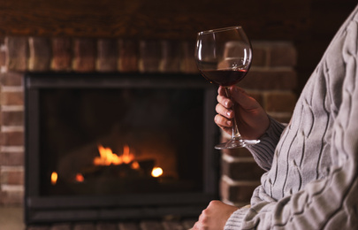 Photo of Man with glass of wine near fireplace at home, closeup