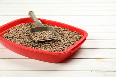 Photo of Cat litter tray with filler and scoop on white wooden floor
