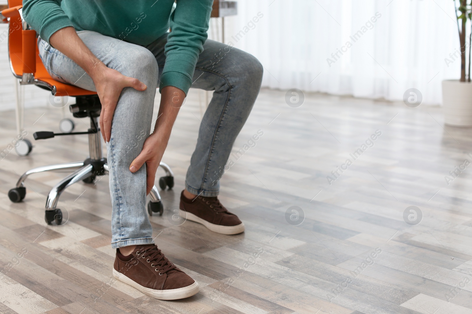 Photo of Man suffering from leg pain indoors, closeup with space for text