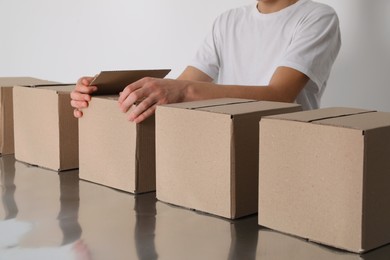 Photo of Man folding cardboard boxes at table, closeup. Production line