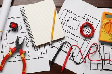 Photo of Flat lay composition with wiring diagrams and digital multimeter on wooden table