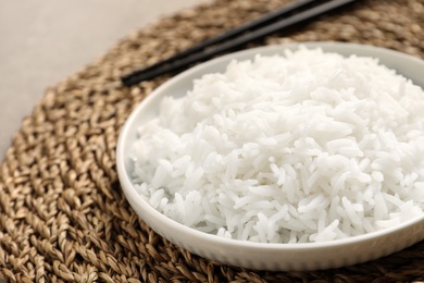 Plate of tasty cooked rice on wicker mat, closeup