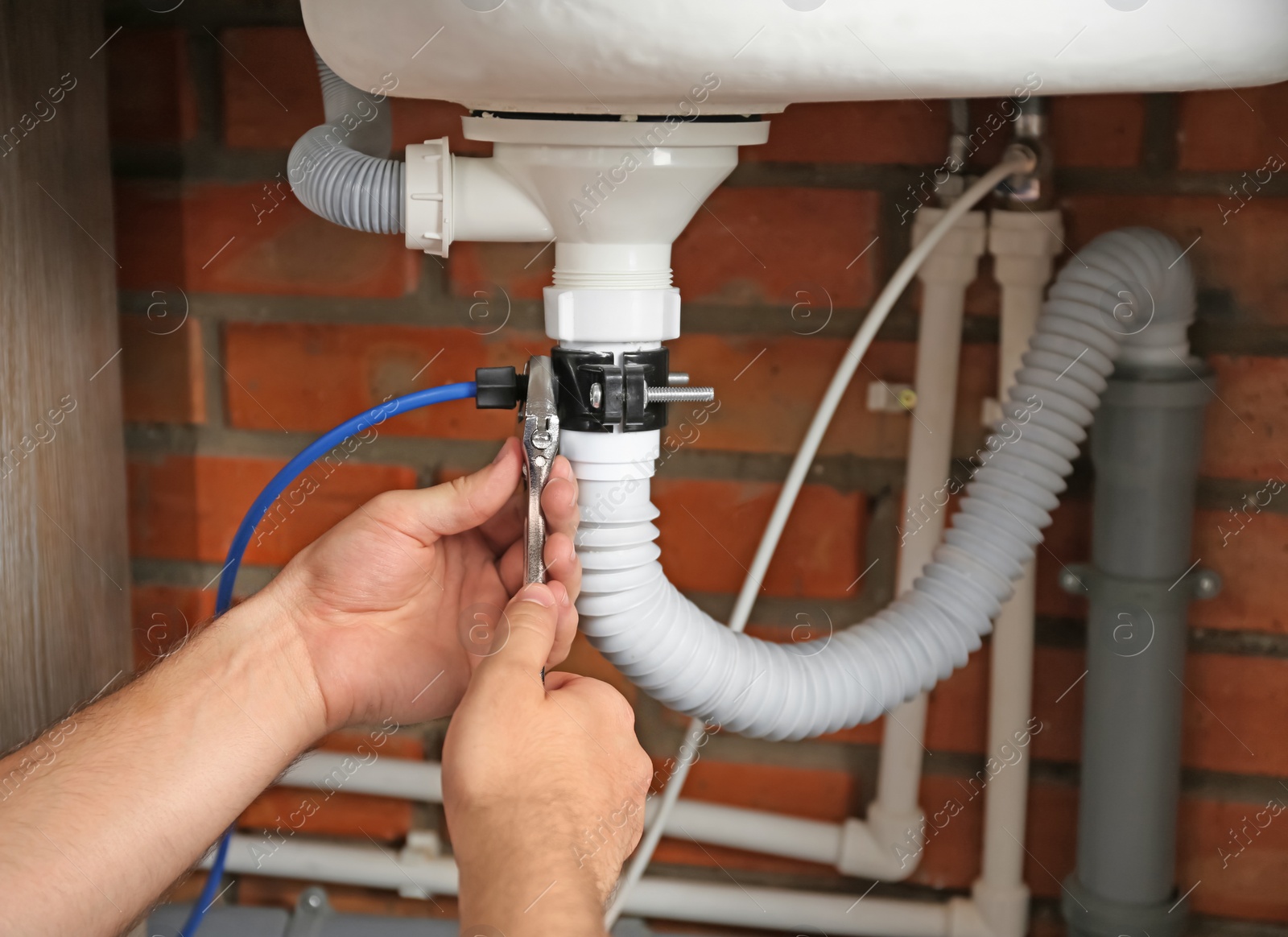 Photo of Professional plumber fixing sink drain, closeup of hands