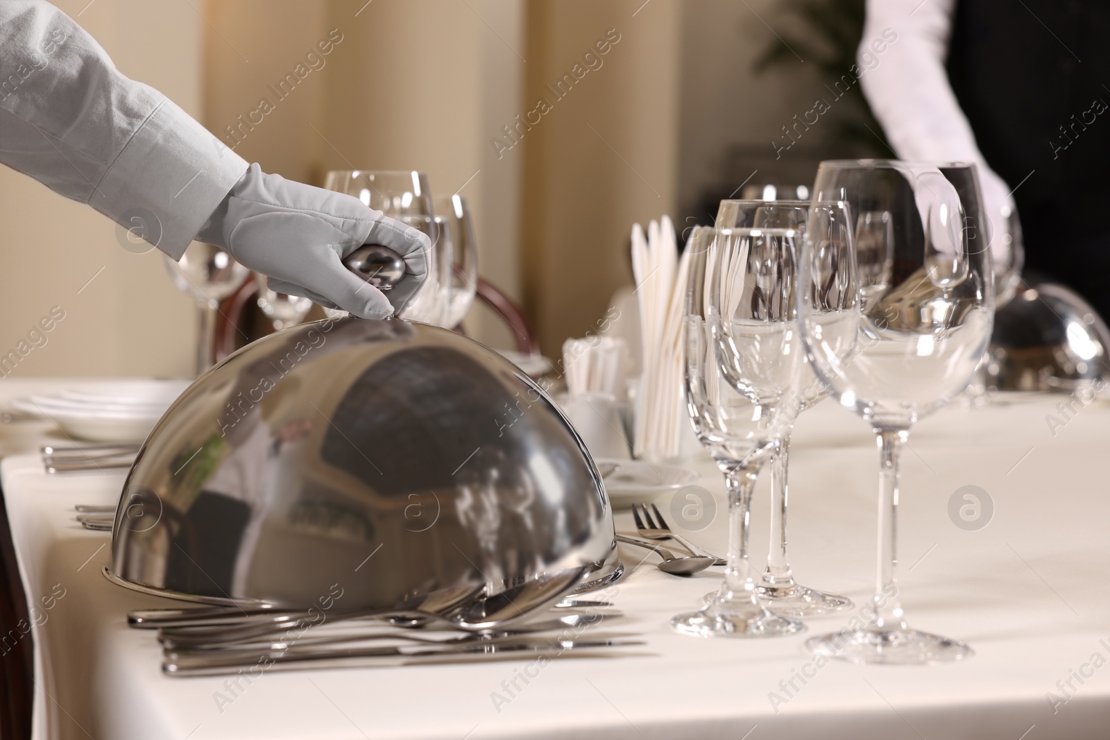 Photo of Woman setting table in restaurant, closeup. Professional butler courses