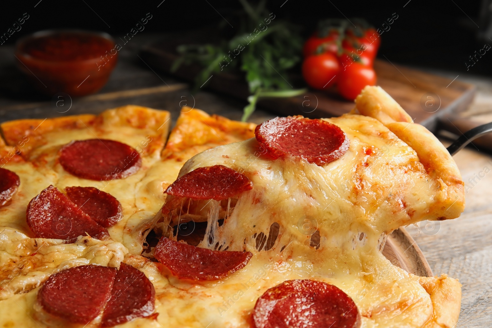 Photo of Taking slice of tasty pepperoni pizza on wooden table, closeup