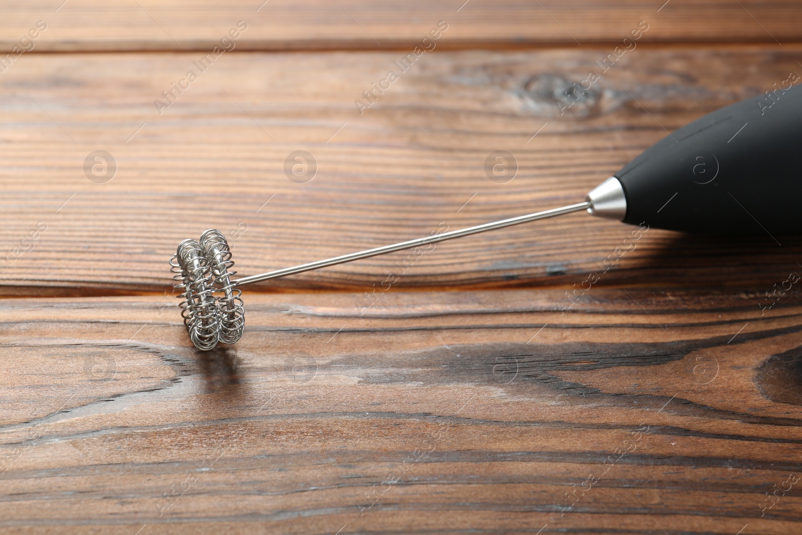 Photo of Black milk frother wand on wooden table, closeup