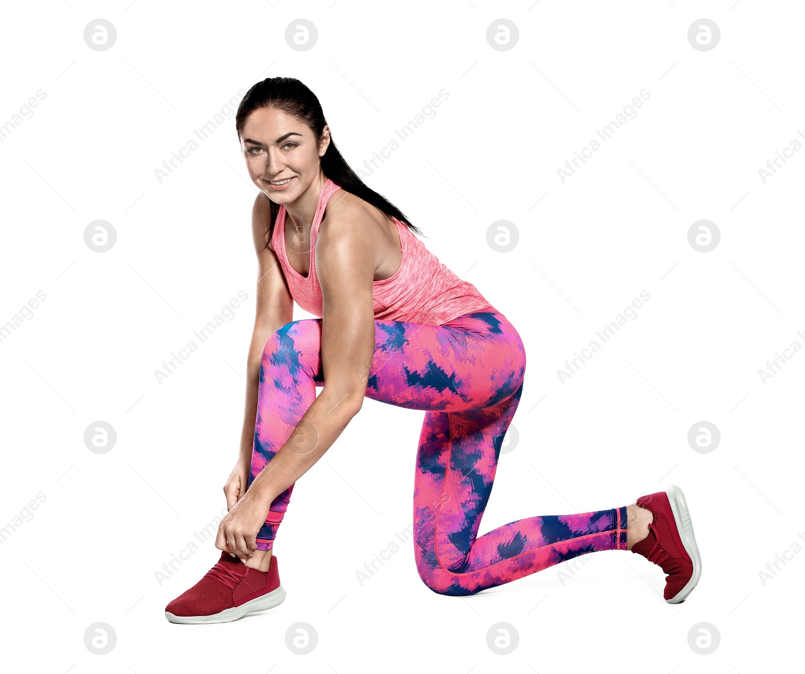 Photo of Beautiful young runner tying shoelaces on white background